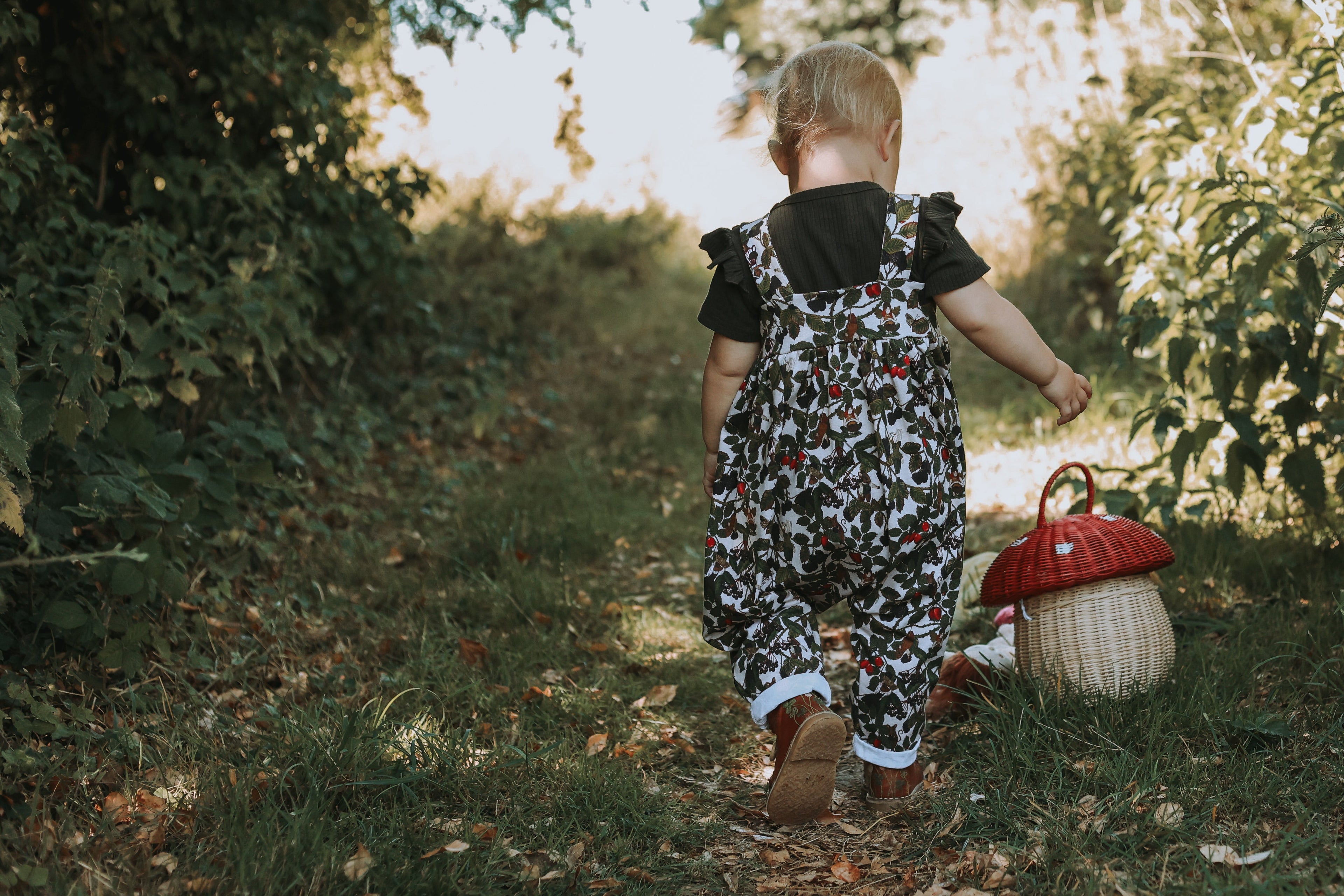 Child walking through a forest with a red basket