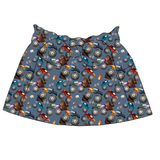 Children’s paperbag skirt in Monster Trucks fabric – denim blue base with monster trucks, flames, ramps and racing details, with bow and pockets.