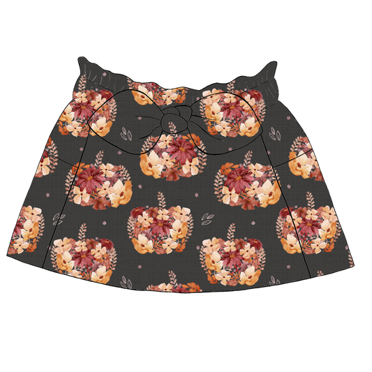 Children’s paperbag skirt in Baize fabric – charcoal base with pumpkin and floral print in warm rust, peach and blush tones, with bow detail.