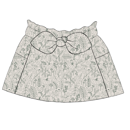 Children’s paperbag skirt in cream fabric with sage green line-drawn pumpkins, mushrooms and autumn leaves, with bow waist and pockets.
