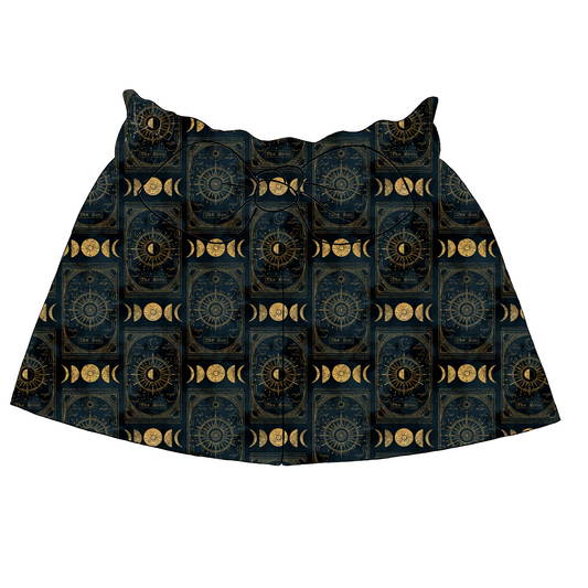 Children’s paperbag shorts in Tarot fabric – navy base with golden celestial motifs including tarot cards, suns and moons, with bow and ruffle waistband.