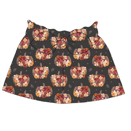 Paperbag shorts for children in Baize fabric – charcoal background with warm florals and pumpkins, ruffled waist and bow tie.