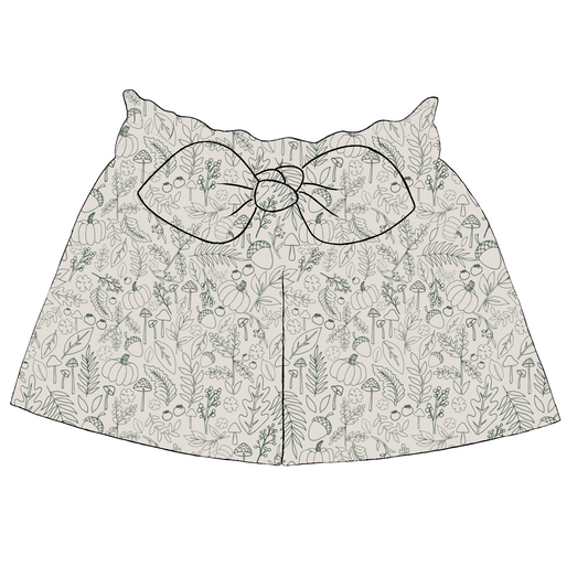 Children’s paperbag shorts in Autumn Outlines – cream fabric with sage green line drawings of mushrooms, pumpkins and leaves, finished with bow detail.