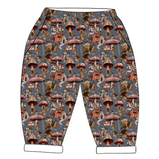Whimsical handmade trousers in Mushroom Town – mushroom houses and snails on blue-grey jersey, with rolled hems and pockets.
