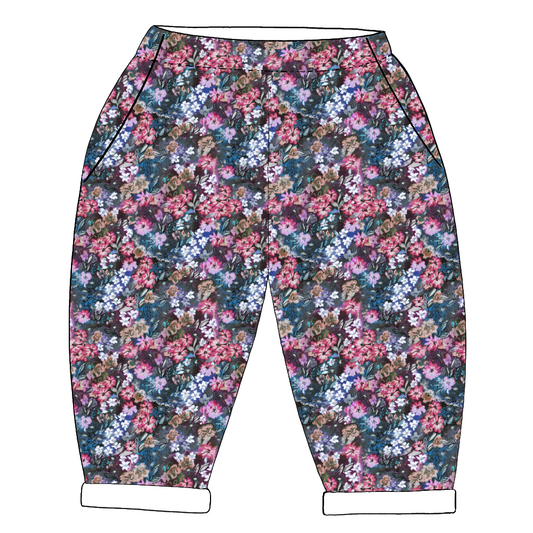 Children’s handmade trousers in Matilda – expressive floral print in fuchsia, violet and green on a deep blue base with rolled hems.