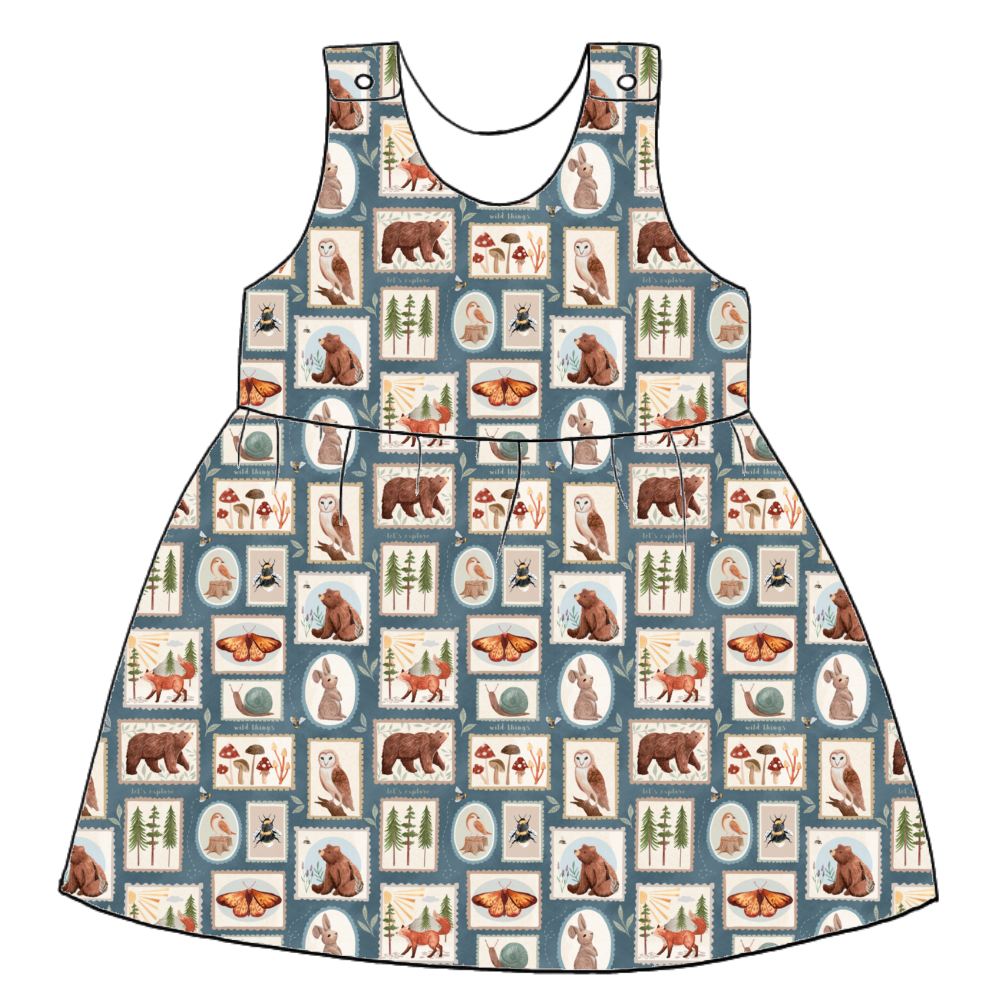 Handmade pinafore dress in Wild Stamps – jersey tile print with woodland creatures, toadstools and folk motifs in dusky blue and rust. Features gathered skirt and popper straps.