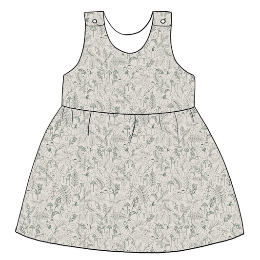 Handmade pinafore dress in Autumn Outlines – warm neutral jersey with fine green botanical illustrations. Features popper straps and gathered skirt.