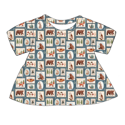 Handmade short sleeved peplum top in Wild Stamps – tile-style woodland print featuring animals, toadstools and trees on a dusky blue background.