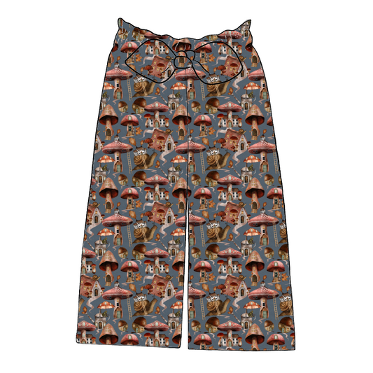 Handmade paperbag trousers in Mushroom Town – dusky blue base with mushroom houses, snails and autumn leaves, finished with wide legs and bow.