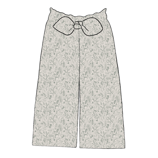 Paperbag style kids’ trousers in Autumn Outlines – soft jersey with fine green foliage and pumpkin sketches on a neutral background.