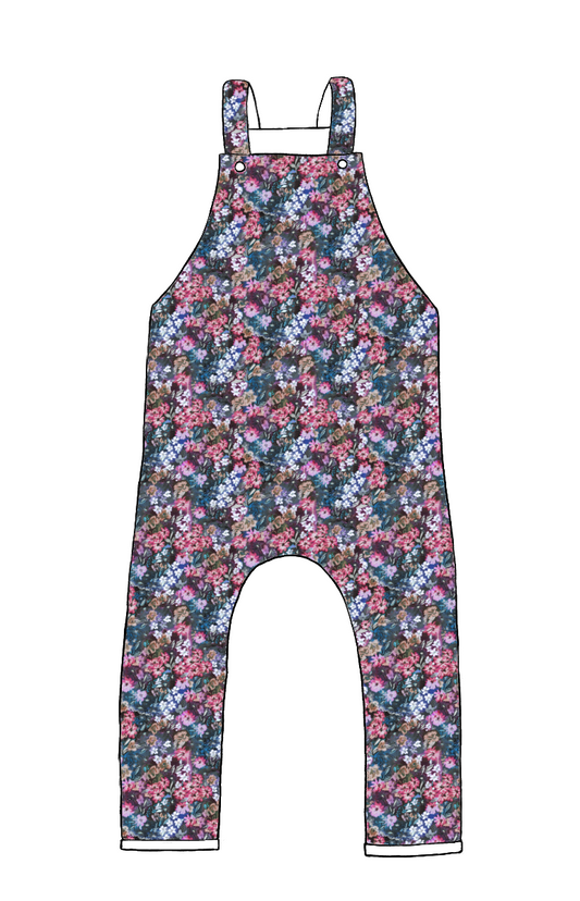 Full-length handmade dungarees in Matilda Floral – vibrant painterly floral print in blue, pink, and violet tones with rolled hem and cross-back straps.